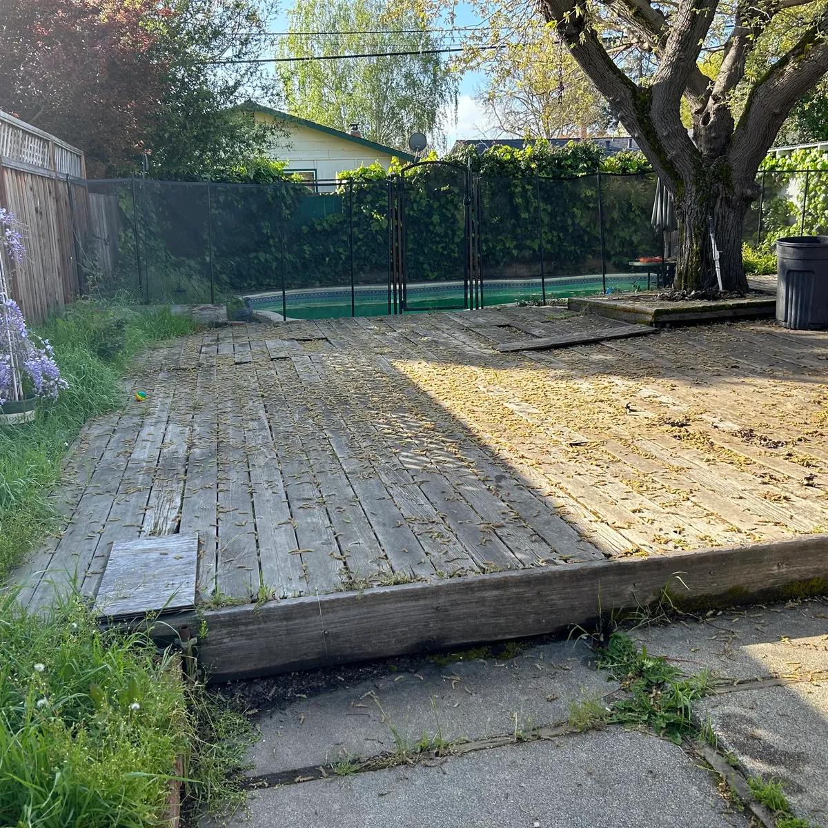 Weathered wood deck covering a backyard before tear-out and removal